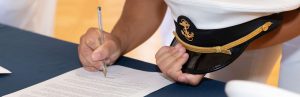 Closeup of a midshipman's hands signing a document