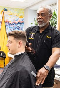 A midshipman having his hair cut in the barber shop