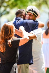 A father and mother hugging their midshipman son