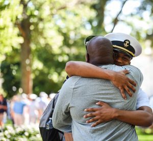 A father giving his midshipman son a hug
