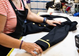 A tailor spreading a uniform out on a table