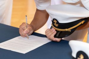 Closeup of a midshipman's hands signing a document