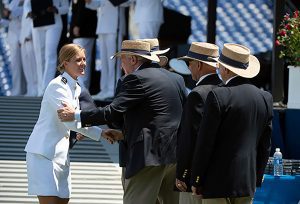 A midshipman shaking hands with a group of alumni