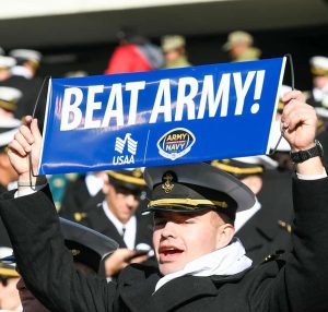 A midshipman holding a sign that reads: Beat Army