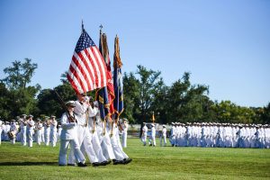 A group of midshipmen marching with flags