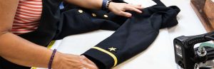 A tailor working on a uniform that is on a table
