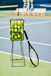 A rack of tennis balls and a tennis racquet
