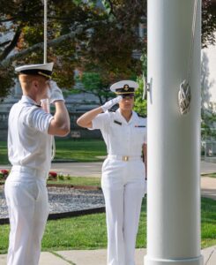 Two midshipmen saluting a flag